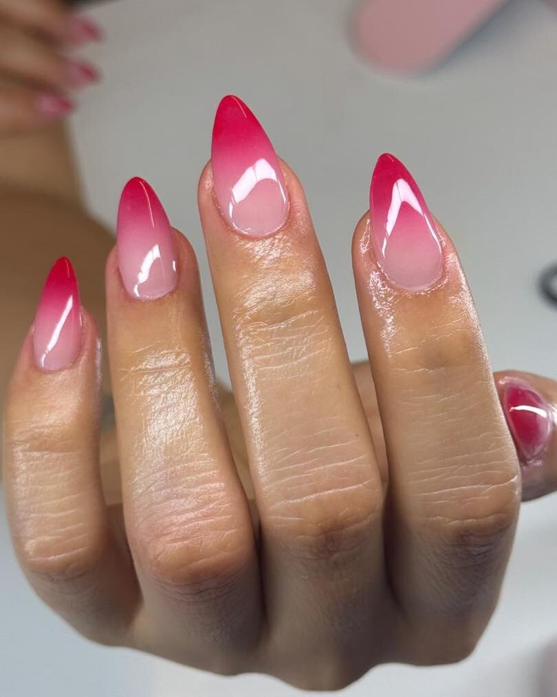 Almond-shaped nails with a glossy pink to red ombré